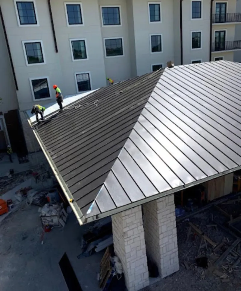 Crew installing standing seam metal roof panels on a commercial project in Steger